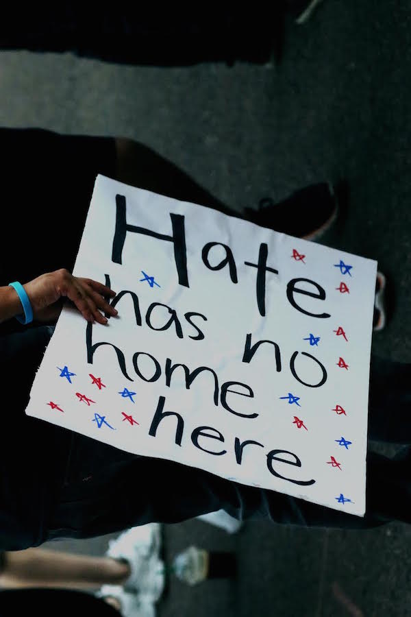 A protester holds up a sign that reads Hate has no home here in black text on a white poster with red and blue stars. Protesters congregated outside the building where President Donald J. Trump held a campaign-style rally on Tuesday, Aug. 22, 2017.