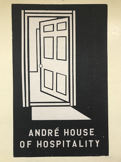 A poster depicting a doorway with text below reading "André House of Hospitality."