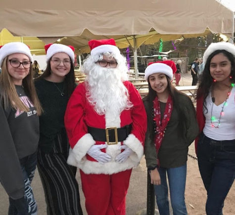 Freshman Emma Valentine, junior Nicole Goldman, sophomore Anna Gomez (Santa), sophomore Janessa Gutierrez and sophomore Brisa Duarte volunteering at the Xavier tent for ZooLights. (Left to Right)