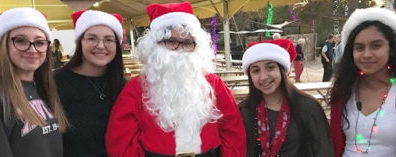 Freshman Emma Valentine, junior Nicole Goldman, sophomore Anna Gomez (Santa), sophomore Janessa Gutierrez and sophomore Brisa Duarte volunteering at the Xavier tent for ZooLights. (Left to Right)