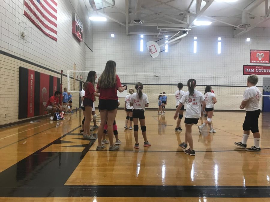 Juniors Alex Lambesis (left) and Hallie Jonkosky (right) are volunteering at the rams gym by aiding the young athletes in a volleyball practice. 