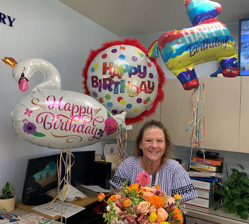 Xavier’s Director of Student Attendance, Jerri Butts, receives flowers and balloons from the president of Xavier’s Dads’ Club, Matt Campisi. Butts was thrilled to be celebrated on her special day.