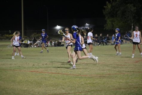 Sophomore McKenna Boyer searches the field to find someone to receive her pressured pass. Xaviers varsity lacrosse team includes various students from all grade levels.