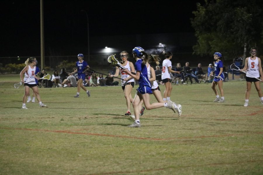 Sophomore McKenna Boyer searches the field to find someone to receive her pressured pass. Xaviers varsity lacrosse team includes various students from all grade levels.