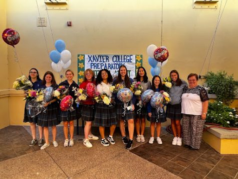 Xavier’s National Merit Semifinalists gather with Sister Joanie for a fun picture after signing their stars for the poster shown behind them. 
