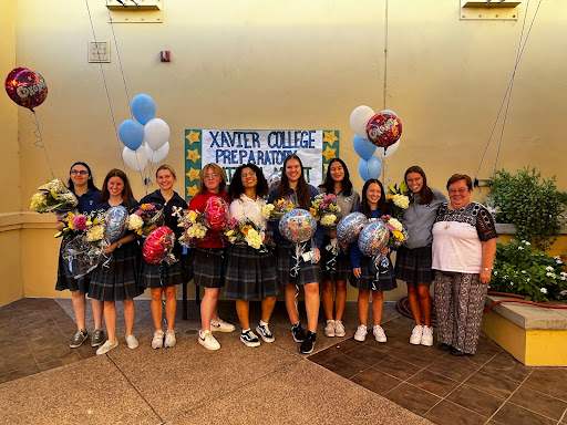 Xavier’s National Merit Semifinalists gather with Sister Joanie for a fun picture after signing their stars for the poster shown behind them. 
