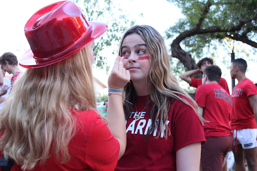 As the Brophy campus fills with eager students, senior Katie Carlson decks out senior Kate Tax in red paint at the first tailgate of the year. Students prepare to storm the stands of the Central High School football field for front row views. 