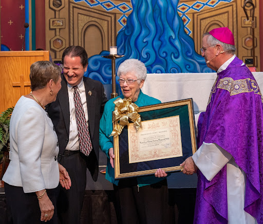 Sister Joan smiles as Bishop Dolan presents her with an honorary plaque for the Pro Ecclesia et Pontifice award. She was joined by Mary Beth Mueller, her former colleague, and Superintendent Domonic Salce who were there to congratulate and support her. 