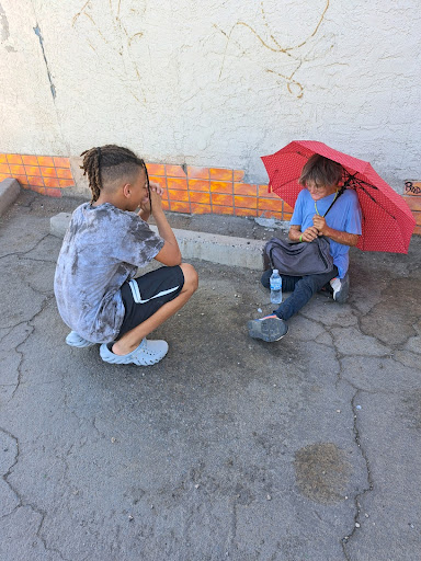 Cam Benson takes a moment of prayer after handing out a bottle of water and umbrella to help a homeless woman in need. At just 13 years old, Benson is excited to be making an impact on his local community. (Photo courtesy of Rhonda Golden)