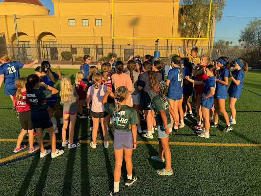The flag football team is joined in the huddle by the girls who attended Youth Flag Football Night on October 16. The girls who attended show their admiration for the team and their excitement for the game against Queen Creek. (Photo courtesy of Camila Felix)