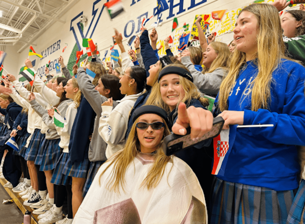 A spirited showcase: Xavier College Preparatory sophomores Olivia Yu and Chloe Cundiff strike a pose after performing their rally dance for the varsity soccer team. Behind them, sophomores enthusiastically cheer as they attempt to win the Winter Sports Rally 2024.