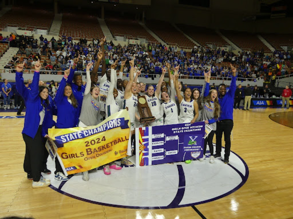 The Xavier basketball team poses victoriously with its championship trophy and banners. All with forefingers up signal Xavier’s historic first-ever championship win. (Photo courtesy of Zachary Carlson)