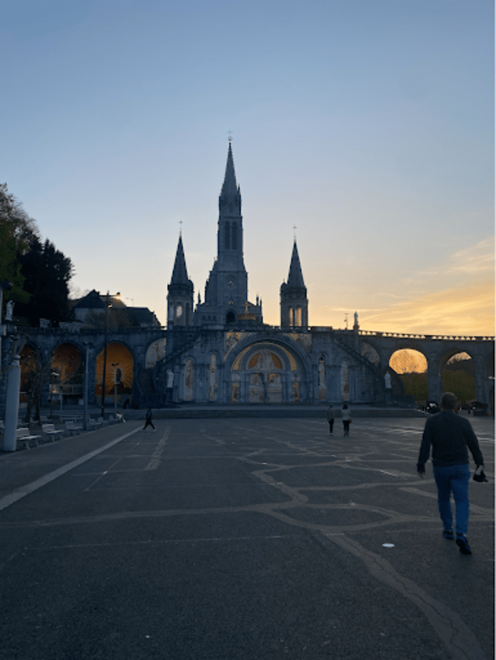 Participants+of+Xavier%E2%80%99s+annual+Lourdes+pilgrimage+walk+in+front+of+the+Basilica+of+Our+Lady+of+the+Rosary+during+sunset%2C+which+is+within+the+Sanctuary+of+Our+Lady+in+Lourdes%2C+France.+On+Easter+Sunday%2C+people+from+all+over+the+world+gather+here+to+say+the+rosary%2C+celebrate+Mass+and+light+candles%2C+illuminating+Easter+night.+It+is+known+as+the+%E2%80%98Lower+Church%2C%E2%80%99+and+is+the+last+out+of+the+three+basilicas+in+Lourdes+to+be+completed.%0A