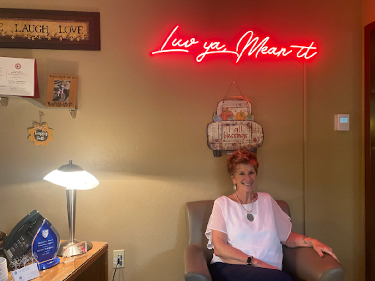 Assistant Principal Denise Macrina sits below a sign with her famous words, “Luv ya, Mean it,” and on her right are recognition awards she has received. She has been in administration since 2012 and previously taught freshman English.