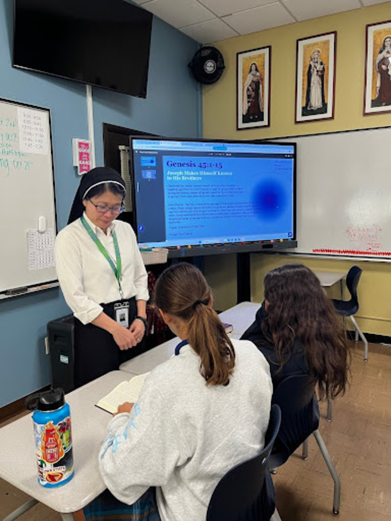 Sister Theresa Trang teaches two students in her classroom. They are reviewing the Bible before an exam.