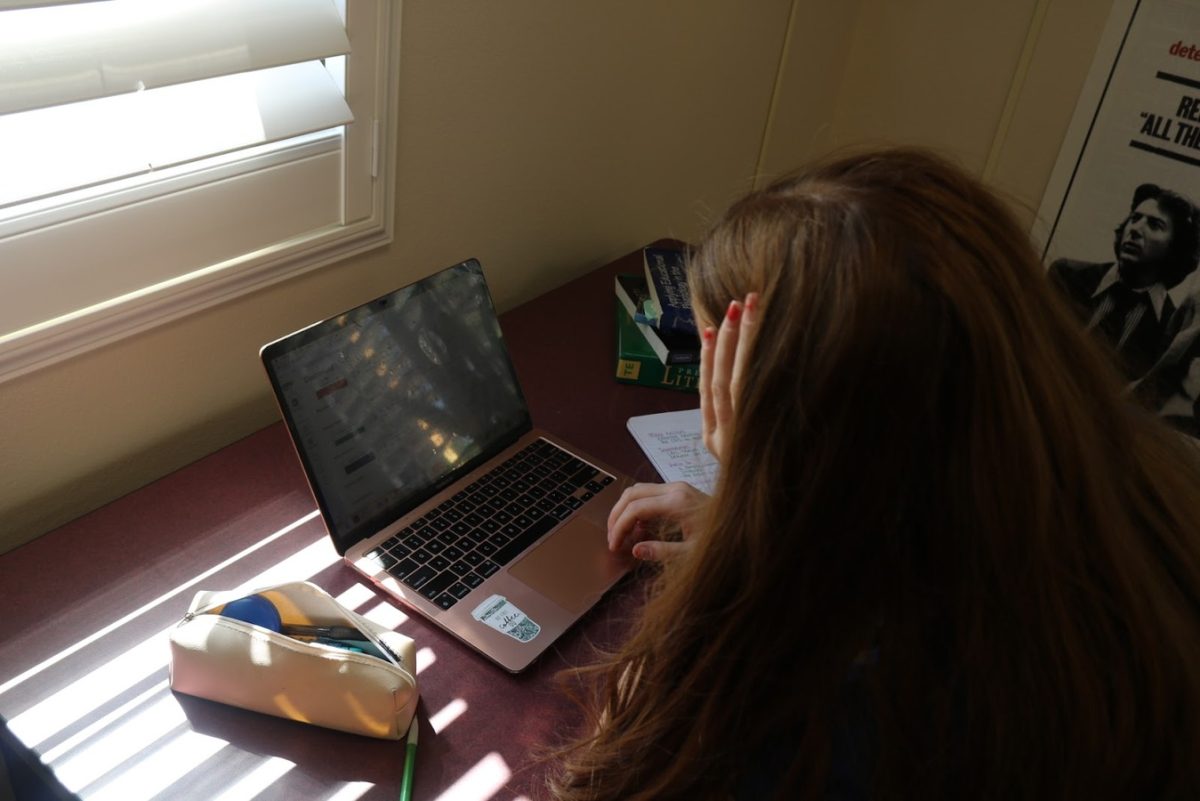 A Xavier student poses in front of a computer and is scrolling through assignments. Students take many rigorous classes that require hours of attention, which for some, is difficult because of familial obligations.  