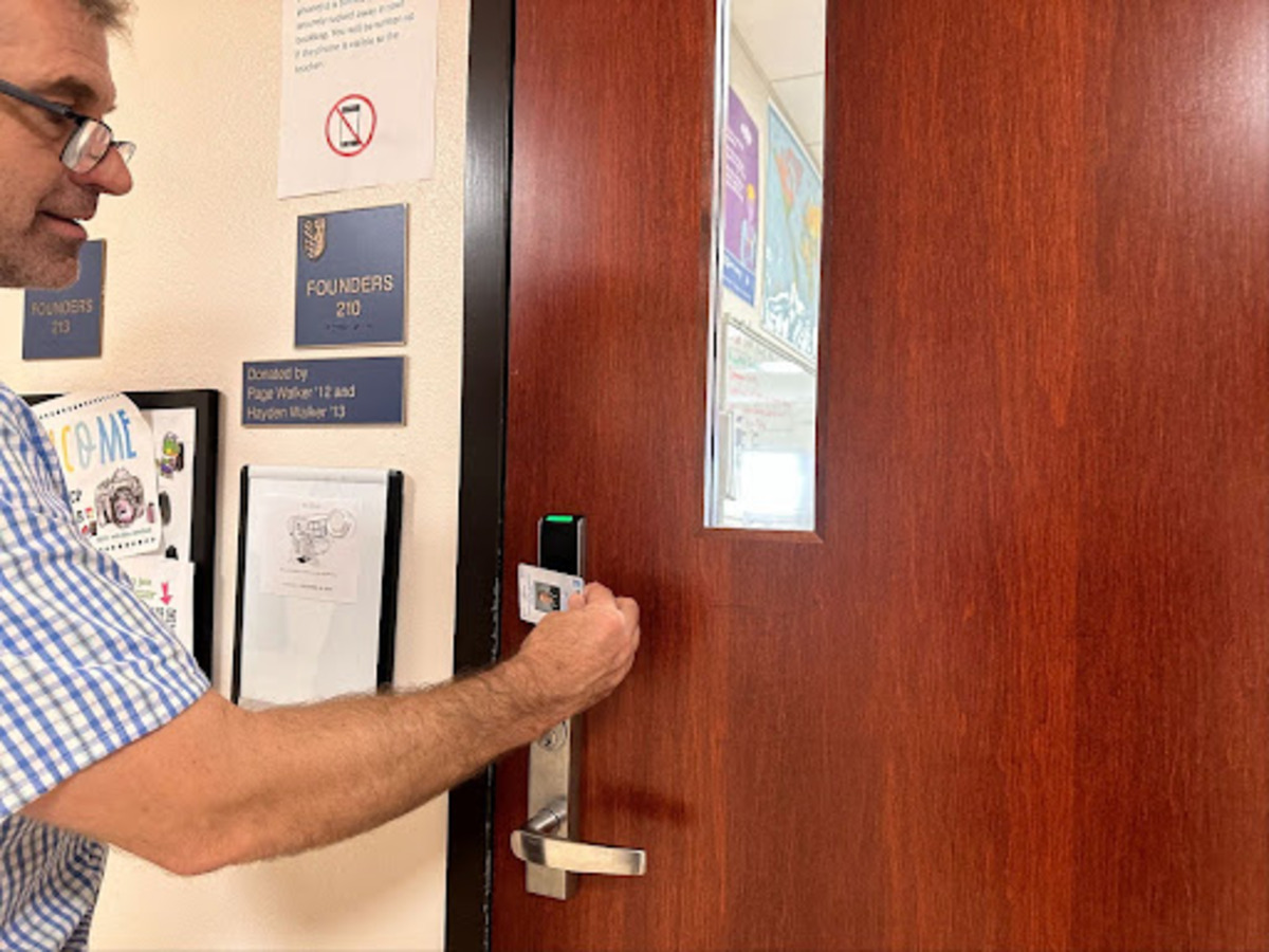 Brian Mostoller, freshman English teacher and XPress moderator, opens the door to his classroom. These newly installed locks allow teachers to open doors with their IDs and can be locked from a remote location in case of emergency. 