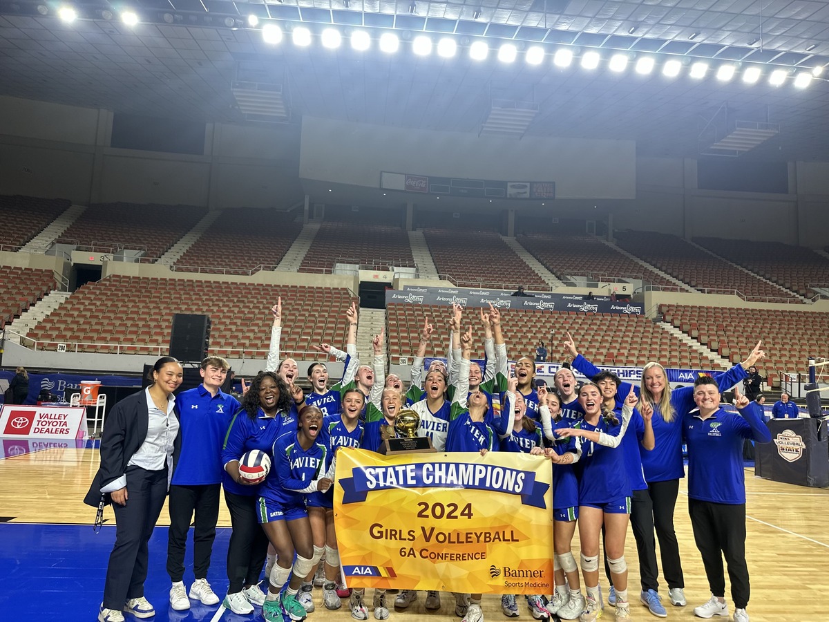 Xavier volleyball cheers in excitement holding the state championship banner and trophy. The Gators ended victoriously in a grueling set. The first set the Gators won 25-16, the second set 25-16, lost the third 17-25 and came up on top 27-25 to win it all.