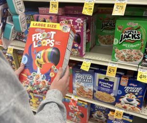 A girl poses with a box of Kellogg’s Froot Loops in the cereal section of the supermarket. On Tuesday, October 15, 2024, a protest was held in front of Kellogg's headquarters to fight for change in the artificial dyes contained in the cereals.