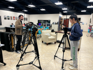 Senior Libby Donaldson works with instructor Eric Lambert to set up cameras in the film room to create a “podcast setup.” This will be used for a student’s film in a current project. 