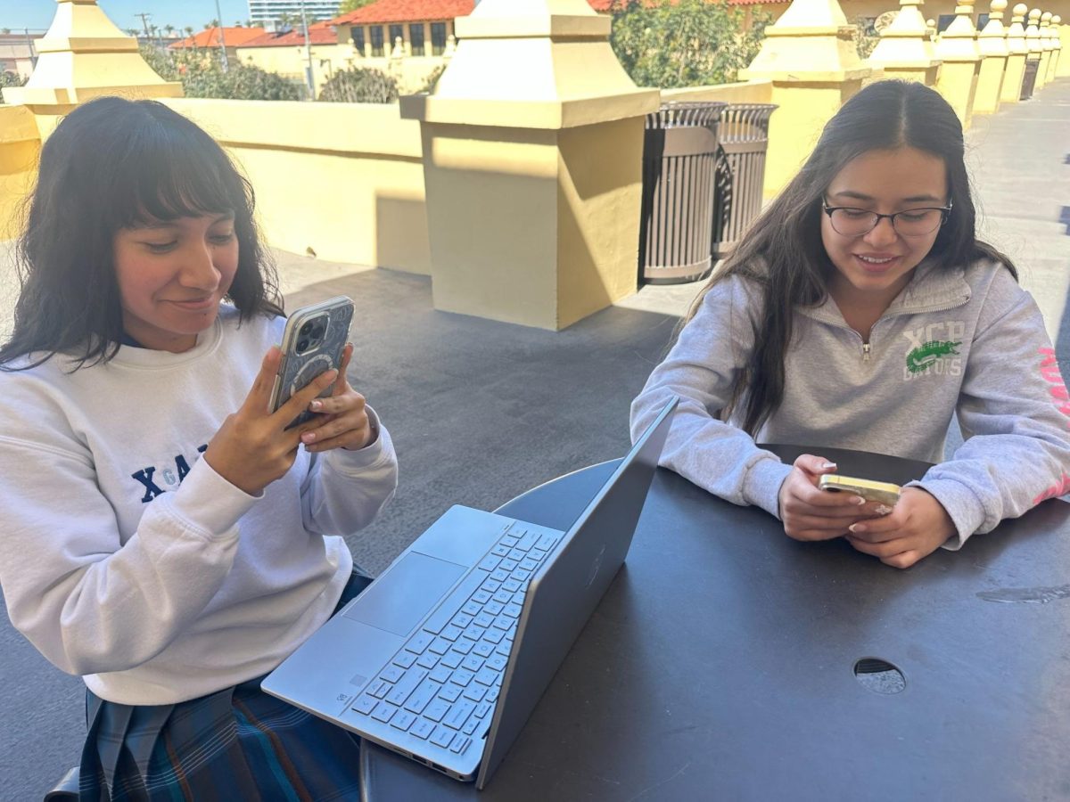 Student Mariana Rodriguez ‘26 is posed using her laptop for a school assignment while using her phone for Artificial Intelligence with Ahlyha Barrios ‘26. This is not a good example of the use of the academic honesty code with technology at Xavier.