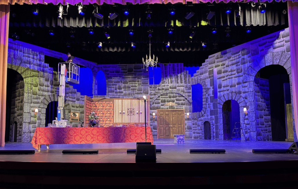 A crew member adjusts the stage lighting during preparations for the fall play. Behind the scenes, students help design and build sets to bring the production to life.