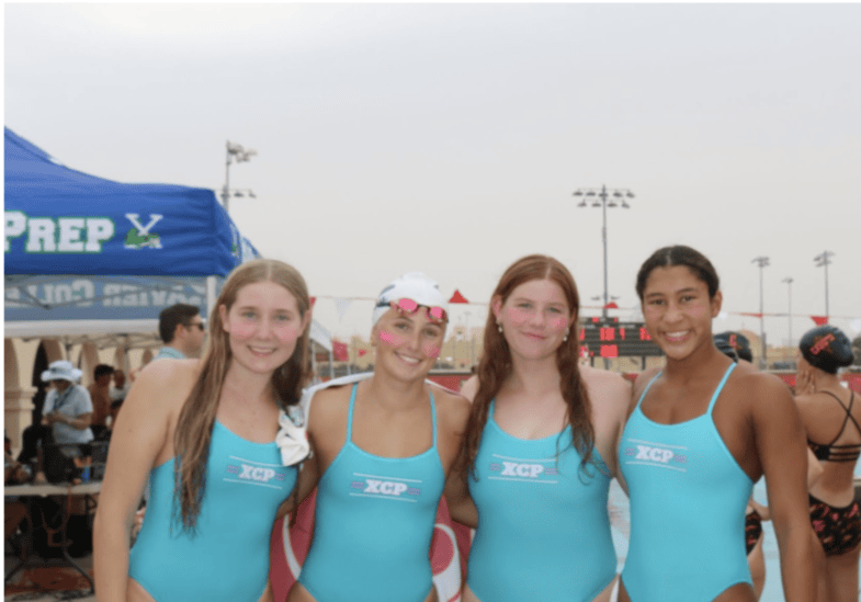 Audrey McEwen ‘26, Raleigh Kaul ‘26, Sophia Dumanski ‘26 and Adriana Lauterborn ‘26 pose for a photo in front of the Brophy pool. They just finished their races for the day.
