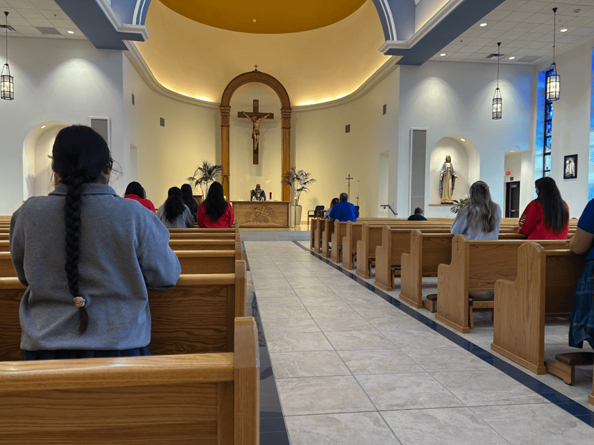 Father Elario Zambakari celebrates Mass on a Friday morning before school. He is preparing for the Eucharist at the altar.