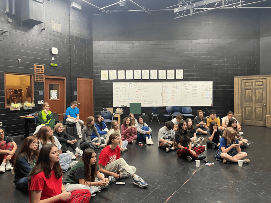 Xavier and Brophy students have a meeting in the Black Box Theater. They listen attentively to a new speaker chosen to discuss the musical aspect of theater. 