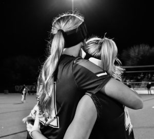 Gigi Bulkley ‘26 and Lucy Coover ‘29 hug on the sidelines of their flag football game. This is the last home game, and Bulkley's last season, and the team has shown togetherness throughout the season.