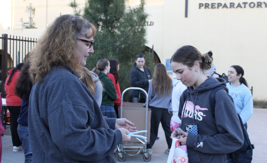 Teresa Corderman hands out a wristband to a student in exchange for a book. She is one of the many teachers who helped to make the Book-a-sweans drive successful.