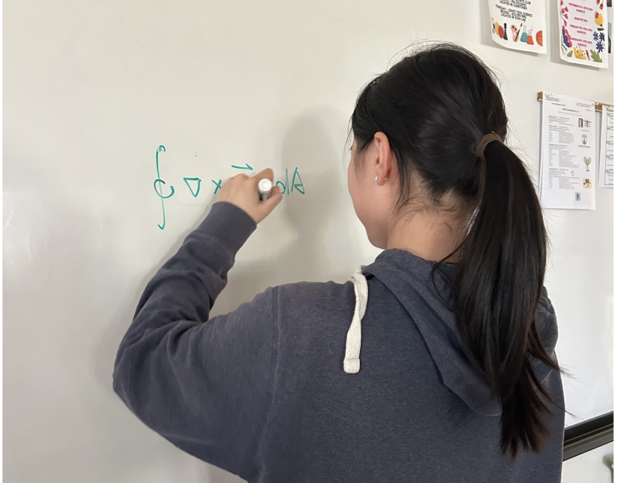 Lai Wei practices a math problem on the whiteboard. She had to practice with many problems like this to compete for the AMC and the AIME.