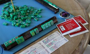 Green Mahjong tiles are spread across a blue mat. This one was left from a match where new players were learning the game.