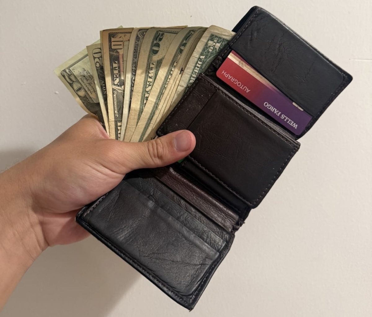  A hand holds an open wallet filled with cash and cards. Managing different forms of money is a part of making everyday financial decisions.

