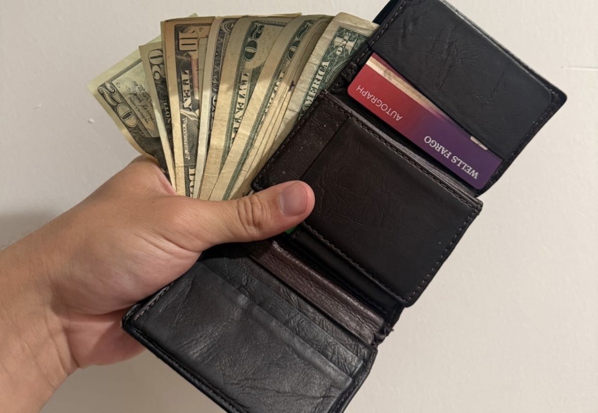  A hand holds an open wallet filled with cash and cards. Managing different forms of money is a part of making everyday financial decisions.

