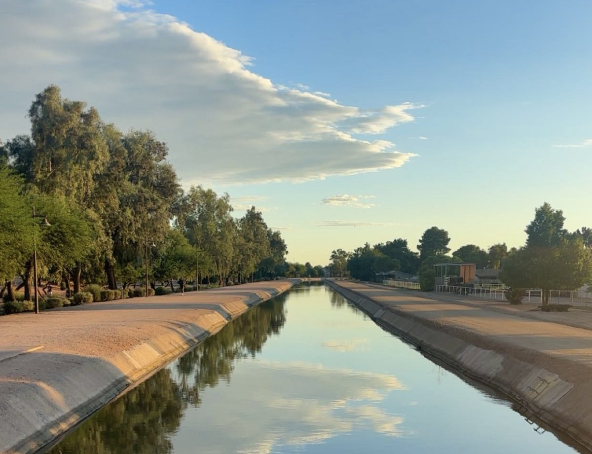 Water flows through the Arizona Canal on October 1 as the state continues to feel the setbacks of the region's ongoing water crisis. The background depicts a mellow mid-day blue sky overlooking the landscape. 
